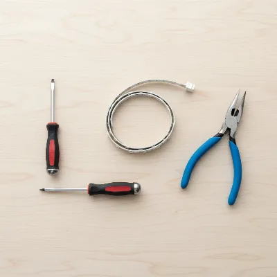 Essential tools for DIY wine cooler LED light replacement including screwdrivers, pliers, and a new light strip.
